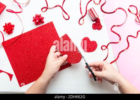 Valentinstag Scrapbook, Hochzeit oder andere Feiertag Dekorationen Hintergrund. Handgemachte Geschenk Grußkarte erstellen, schneiden. Die Hände der Frauen halten die Stockfoto