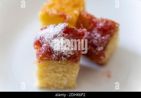 Scheibe Erdbeermarmelade bedeckt Kuchen mit Streuseln von Kokosnuss Stockfoto