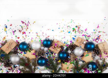 Neujahrs- und Weihnachtsdekoration aus Tannenzweigen, Zapfen, Perlen, Glitzer und blauen und silbernen Kugeln auf weißem Hintergrund. Speicherplatz kopieren. Stockfoto