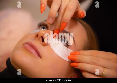 Nahaufnahme der Wimpernverlängerung Verfahren mit Klinikmeister und ein Kunde in einem Schönheitssalon Stockfoto