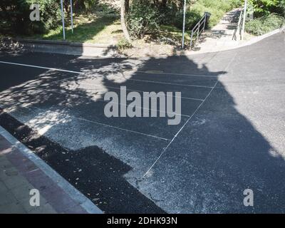 Frisch asphaltierte Straße mit dünnen weißen Linien mit Schatten gesäumt Von den Bäumen an einem Sommertag Stockfoto