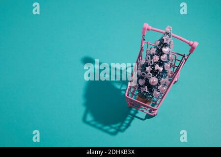 Pinker Warenkorb mit dekorierten Weihnachtsbaum auf aquafarbenem Hintergrund. Stockfoto