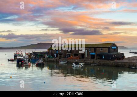 Lyme Regis, Dorset, Großbritannien. Dezember 2020. Wetter in Großbritannien. Die Wolken leuchten orange bei Sonnenuntergang über dem historischen Cobb Harbour bei Lyme Regis in Dorset. Bild: Graham Hunt/Alamy Live News Stockfoto