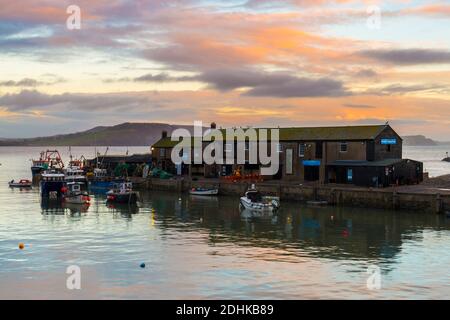 Lyme Regis, Dorset, Großbritannien. Dezember 2020. Wetter in Großbritannien. Die Wolken leuchten orange bei Sonnenuntergang über dem historischen Cobb Harbour bei Lyme Regis in Dorset. Bild: Graham Hunt/Alamy Live News Stockfoto