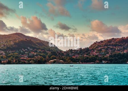 Comer See wunderschöne Landschaft türkisfarbener Wasserhorizont mit Städten und Dörfern an anderen Ufern und Bergen in der Lombardei, Italien Stockfoto