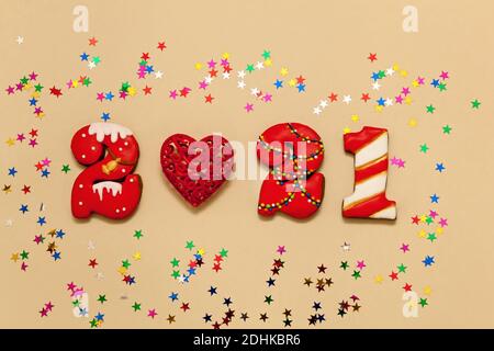 Zahlen 2021 aus Lebkuchengebäck in mehrfarbiger Glasur auf beigem Hintergrund. Rotes Herz und bunte Sterne. Neujahr 2021, Weihnachten h Stockfoto