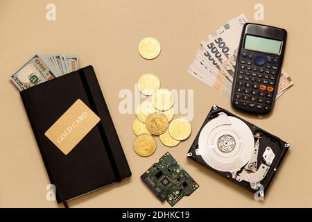 Geschäftskonzept-Artikel auf dem Tisch Goldbitcoins, Dollar, Tagebuch, Goldkarte, Festplatte auf beigem Hintergrund. Bitcoins sind eine digitale Währung, die gl Stockfoto