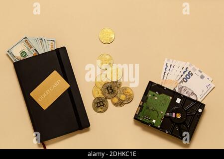 Geschäftskonzept-Artikel auf dem Tisch Goldbitcoins, Dollar, Tagebuch, Goldkarte, Festplatte auf beigem Hintergrund. Bitcoins sind eine digitale Währung, die gl Stockfoto