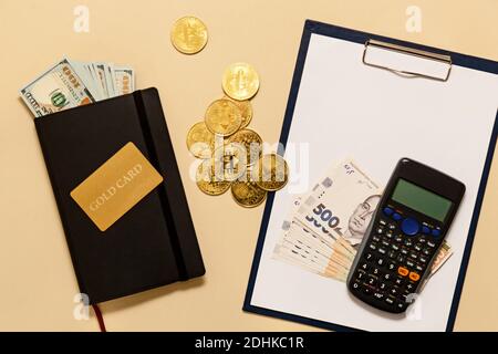 Geschäftskonzept-Artikel auf dem Tisch Goldbitcoins, Dollar, Tagebuch, Goldkarte, Rechner auf beigem Hintergrund. Bitcoins sind eine digitale Währung, die g Stockfoto