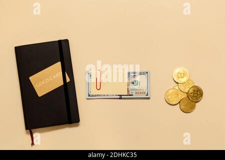 Geschäftskonzept-Artikel auf dem Tisch Goldbitcoins, Dollar, Tagebuch, Goldkarte, auf beigem Hintergrund. Bitcoins sind eine digitale Währung, die globale Marke Stockfoto