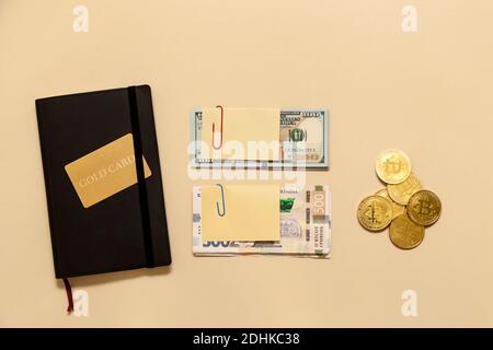 Geschäftskonzept Artikel auf dem Tisch Goldbitcoins, Dollar, ukrainische Griwna, Tagebuch, Goldkarte, auf einem beigen Hintergrund. Bitcoins sind eine digitale Currenc Stockfoto