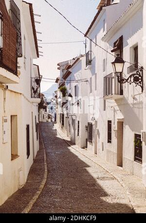 ALTEA, SPANIEN - Sep 20, 2020: Charmante traditionelle weiße Gebäude auf einer Straße in der Stadt Altea mit Felsen Asphalt. Stockfoto