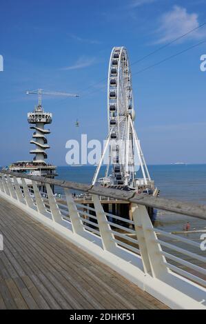 Scheveningen, Niederlande - 10. August 2020: Bungee-Jumping-Turm und großes Riesenrad am berühmten Strand in Scheveningen, Niederlande. Stockfoto