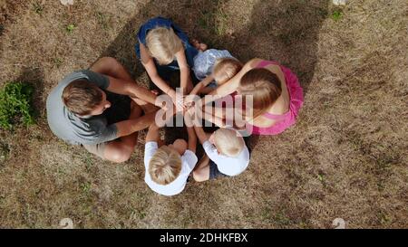 Eine freundliche Familie verbindet die Hände als Zeichen der Einheit und Stärke der Familie. Drohnenansicht. Stockfoto