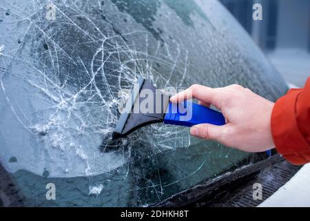 Eis verkrustet auf Autoscheiben. Der Fahrer kratzt Eis von der Windschutzscheibe. Eisiger Regen, Anomalien der Natur Stockfoto