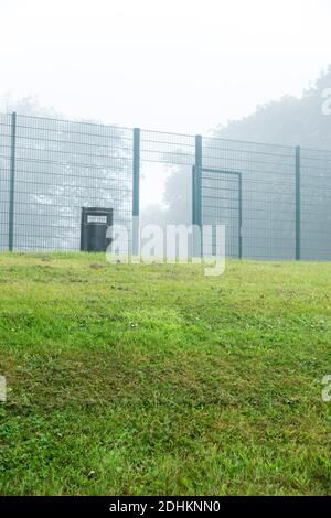 Ein Tor zu einem umzäunten Tennisplatz in einem Park an einem nebligen Tag in Consett, County Durham, Großbritannien Stockfoto