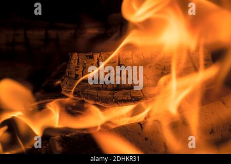 Ein loderndes Feuer im Dunkeln. Entzündung des Brennholzes im Feuer. Ein helles brennendes Feuer. Funken und Flammen in der Dunkelheit. Rot-heiße Hitze und Zunge Stockfoto