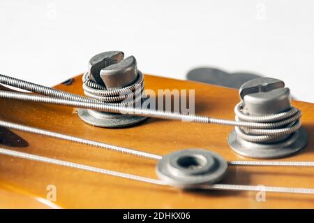 Detail eines Stimmpfostens auf dem hölzernen Kopfteil einer E-Bass-Gitarre. Musikinstrumente und Mechanik für Saitenstimmung. Stockfoto