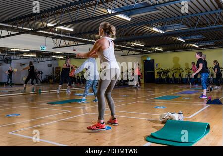 Frauen, die in Übung Workout-Klasse im Fitnessstudio mit sozialen Distanzmarken auf dem Boden trainieren, North Berwick Enjoy Leisure Sports Centre, Schottland, Großbritannien Stockfoto