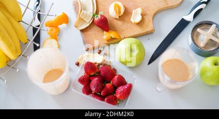 Frische Erdbeeren, grüne Äpfel und Bananen werden geschnitten und zu einem frischen Frucht-Smoothie gemischt. Stockfoto