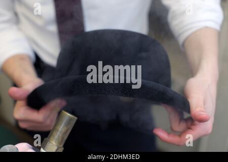 Lock & Co Hatters in London, die einen Bowler-Hut dampfen, um seine ursprüngliche Form wiederherzustellen. Stockfoto