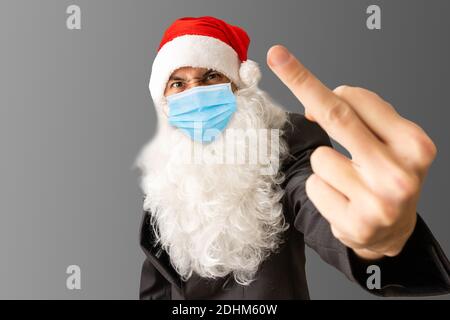 Böse brutal lustig alt bärtig böse böse böse böse Weihnachtsmann trägt Kostüm, Brille, Gesichtsmaske zeigt Mittelfinger Hand Geste isoliert auf Stockfoto