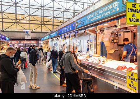 Huelva, Spanien - 11. Dezember 2020: Innerhalb des Mercado del Carmen Marktes. Menschen kaufen Meeresfrüchte, tragen schützende Gesichtsmaske durch COVID-19 Coronavirus Stockfoto