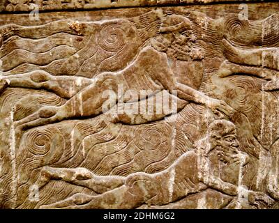 Assyrische Exponate im British Museum in London. Dieses Wandrelief zeigt Krieger, die über den Fluss schwimmen, auf aufgeblasenen Blasen Stockfoto