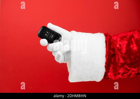 Santa Claus Hand hält Autoschlüssel. Frohe Weihnachten und Neujahrskonzept. Neues Auto Smart Key. Käufer, Immobilien, kaufen, mieten, verkaufen, LKW, Autos Konzept Stockfoto