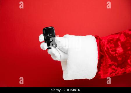 Santa Claus Hand hält Autoschlüssel. Frohe Weihnachten und Neujahrskonzept. Neues Auto Smart Key. Käufer, Immobilien, kaufen, mieten, verkaufen, LKW, Autos Konzept Stockfoto