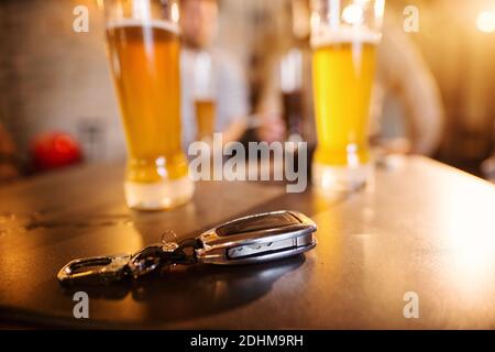 Nahaufnahme der Autoschlüssel auf dem Bartisch vor Gläsern mit Bier vom Fass. Stockfoto