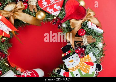 Schöne Weihnachten handgemachte rustikalen Kranz auf rotem Hintergrund. Hergestellt mit Pinienzapfen, Kugeln und Blättern Stockfoto