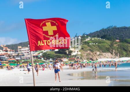 ARRAIAL DO CABO, RIO DE JANEIRO, BRASILIEN - 26. DEZEMBER 2019: Warnzeichen einer roten Flagge am Praia Grande. Im Hintergrund Menschen am Strand. Stockfoto