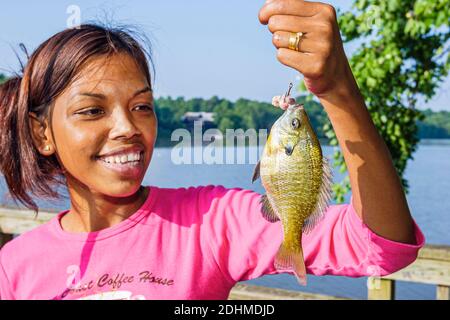 Tuscaloosa Alabama, Warrior River Riverwalk, Schwarzes asiatisches jugendliches Mädchen fangen gefangenen Fisch angeln, Stockfoto