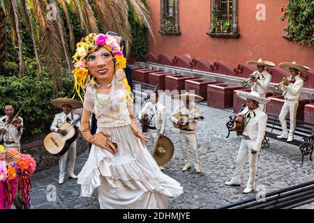 Eine traditionelle mexikanische Mariachi-Band spielt als riesige Puppen namens Mojigangas Tanz während einer Hochzeitsfeier im Lavaderos del Chorro Park in San Miguel de Allende, Guanajuato, Mexiko. Stockfoto