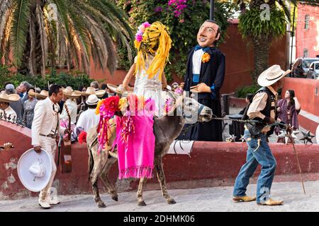 Eine traditionelle mexikanische Mariachi-Band spielt als riesige Puppen namens Mojigangas Tanz während einer Hochzeitsfeier im Lavaderos del Chorro Park in San Miguel de Allende, Guanajuato, Mexiko. Stockfoto