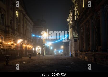 An einer Winternacht auf der Corn Street in Bristol sind Weihnachtsdekorationen in Nebel gehüllt. Stockfoto