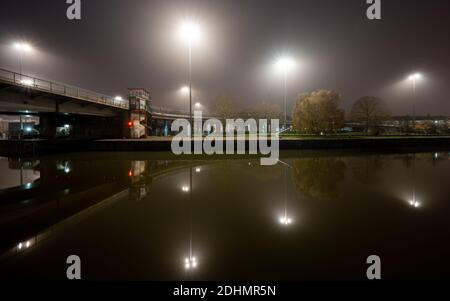 Straßenlaternen werden von Nebel aus dem Cumberland Basin bei einer Herbstnacht auf Bristol's Floating Harbour verbreitet. Stockfoto