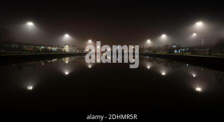 Straßenlaternen werden von Nebel aus dem Cumberland Basin bei einer Herbstnacht auf Bristol's Floating Harbour verbreitet. Stockfoto