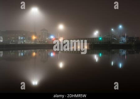 Straßenlaternen werden von Nebel aus dem Cumberland Basin bei einer Herbstnacht auf Bristol's Floating Harbour verbreitet. Stockfoto