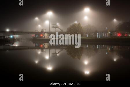 Straßenlaternen werden von Nebel aus dem Cumberland Basin bei einer Herbstnacht auf Bristol's Floating Harbour verbreitet. Stockfoto