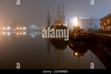 Historische Schiffe werden an den Kais von Bristol's Floating Harbour in einer nebligen Herbstnacht vertäut. Stockfoto