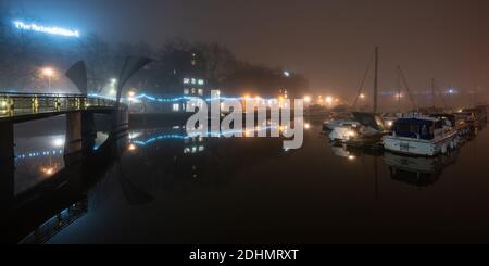 Gebäude und Boote am Hafen sind in einer Herbstnacht im schwimmenden Hafen von Bristol neben der Pero's Bridge in Nebel gehüllt. Stockfoto