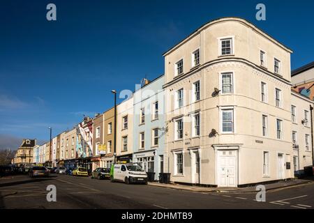 Die Sonne scheint auf traditionellen Reihenhäusern mittlerer Dichte und kleinen Geschäften an der Midland Road im Old Market Viertel von Bristol. Stockfoto