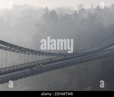 Radfahrer fahren an einem nebligen Morgen in Bristol über die berühmte Clifton Suspension Bridge. Stockfoto