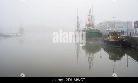 Historische Schiffe, die vor dem M Shed Museum vertäut sind, verblassen im Herbstnebel am schwimmenden Hafen von Bristol. Stockfoto