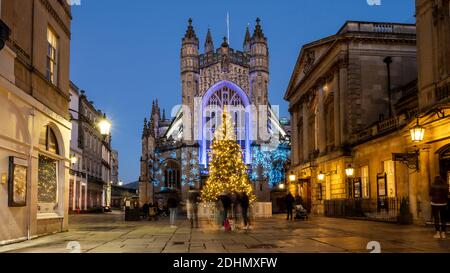 Ein weihnachtsbaum wird in der Dämmerung in Bath Abbey Church Yard, außerhalb der Abtei und römischen Bädern Gebäude beleuchtet. Stockfoto