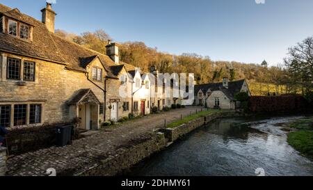 Rauch steigt aus den Schornsteinen der traditionellen Cotswolds auf der Water Lane im malerischen Dorf Castle Combe in Englands Cotswolds. Stockfoto