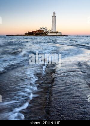 Wellen, Strömung gegenüber der St. Maria Island Causeway in der Dämmerung, mit St Mary's Leuchtturm hinter, auf der Whitley Bay Küste von Tyneside. Stockfoto