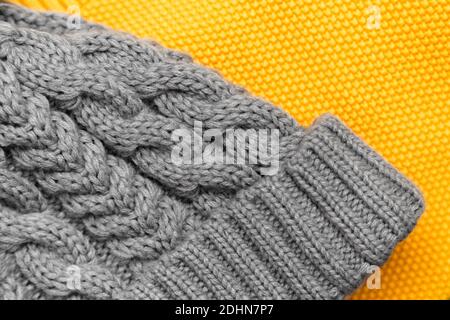 Nahaufnahme von gelbem Strickpullover und grauer Mütze in trendigen Farben. Farben des Jahres 2021. Kuschelige Strickkleidung, warmes Konzept Stockfoto